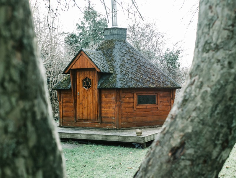 A large hut with a grey colored chimney on top of it.